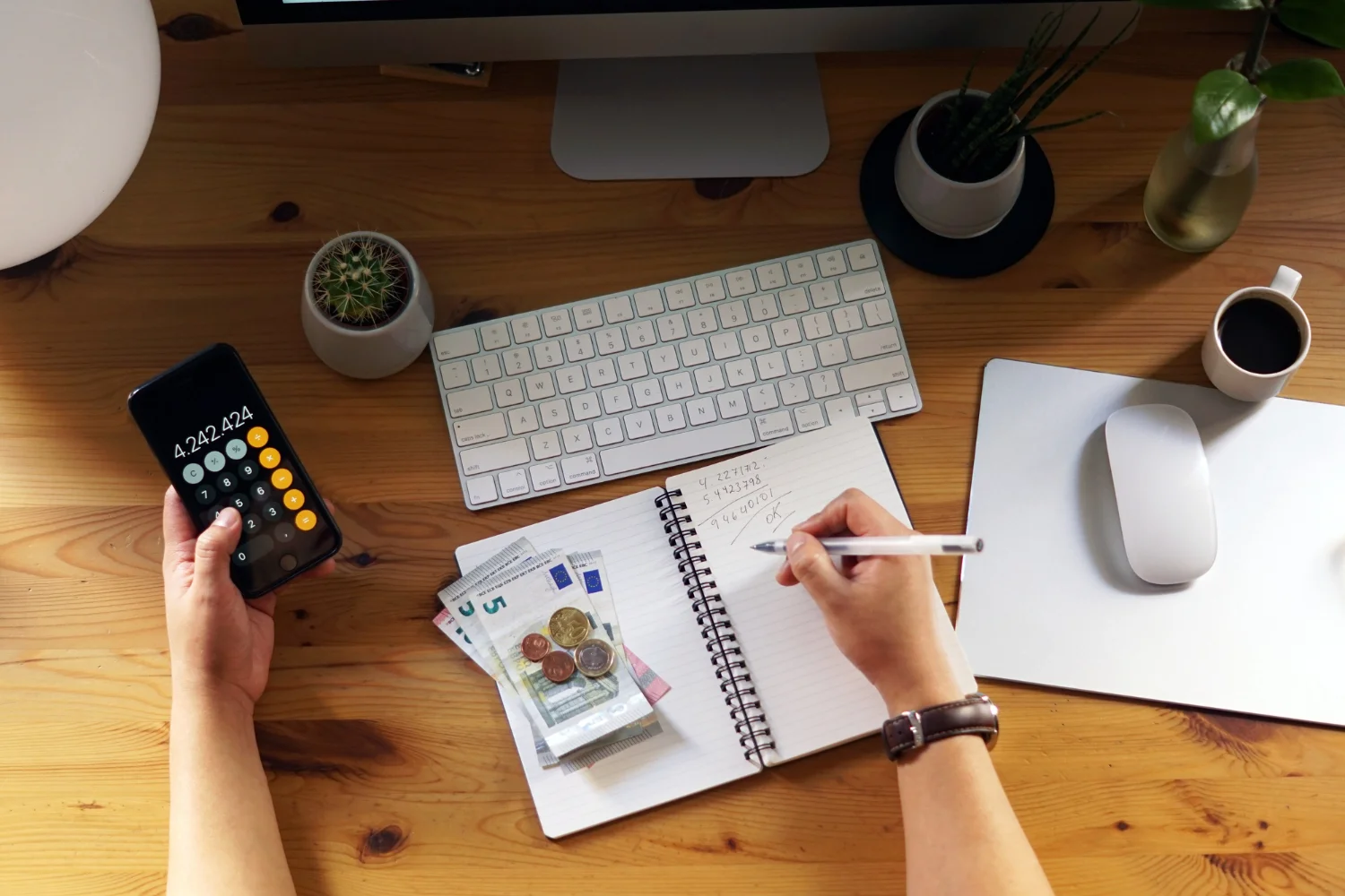 A workspace featuring a calculator, cash, notebook, and computer accessories, illustrating financial planning and organization.