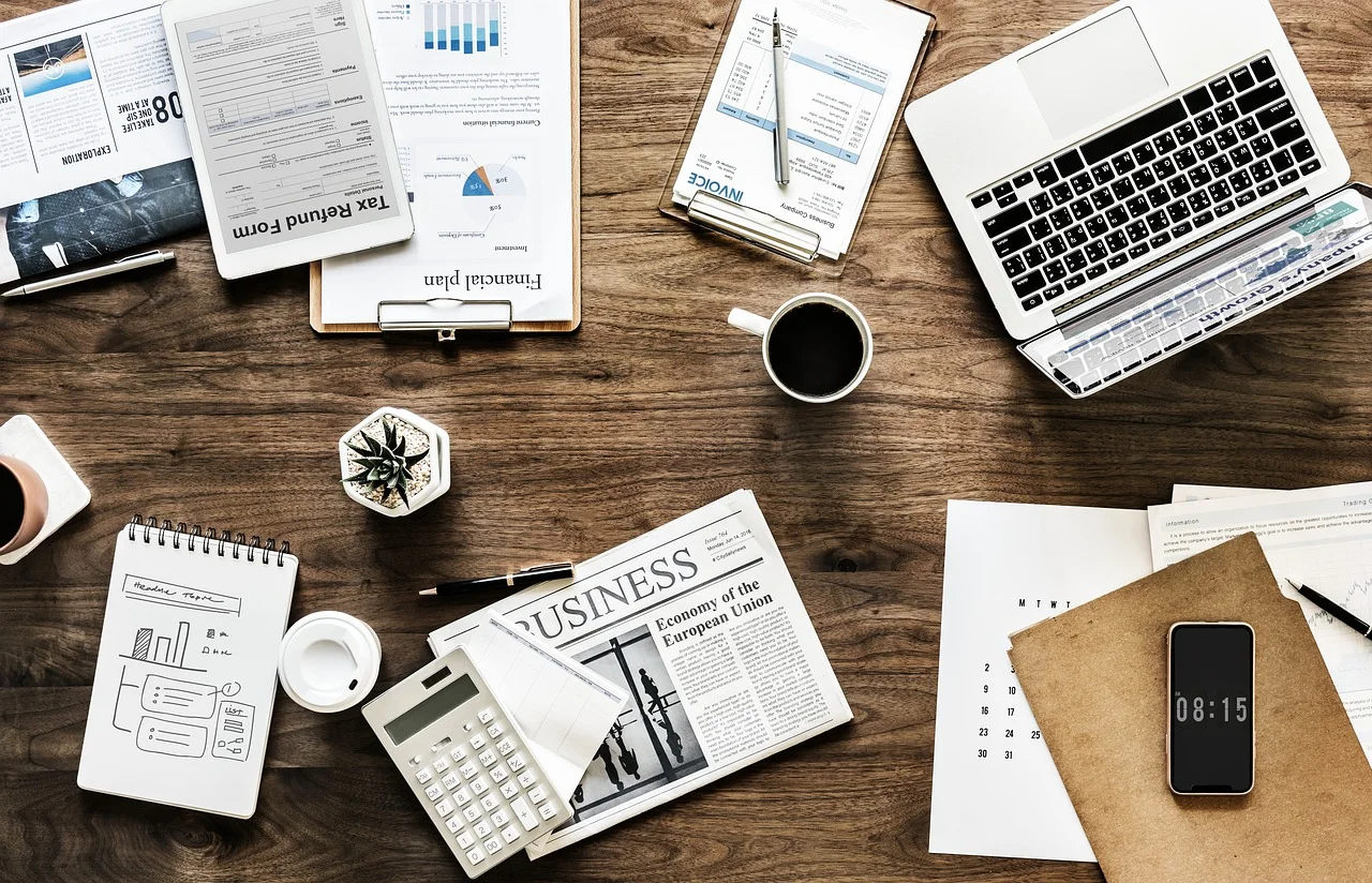 A business workspace featuring a laptop, documents, a calculator, and a coffee cup, ideal for productivity and organization.