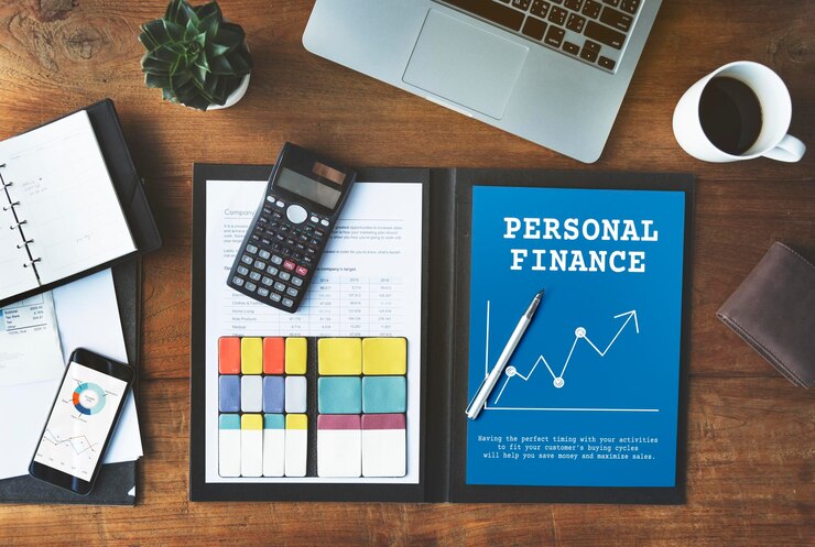 Personal finance planning materials including a calculator, notebook, and documents on a wooden desk.