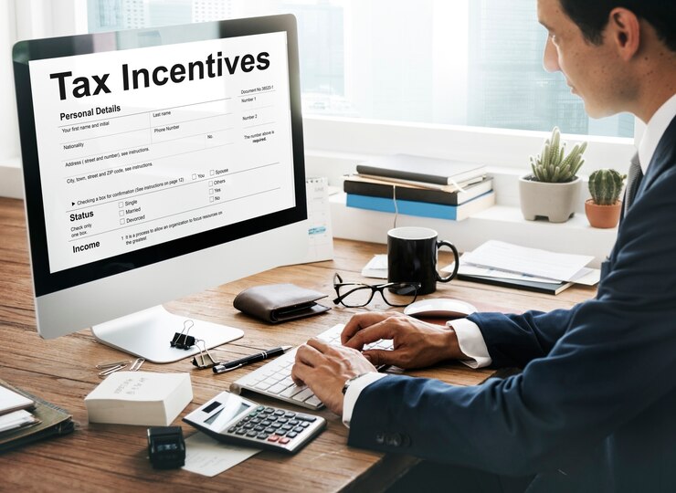 A person reviewing tax incentives on a computer screen with a calculator and documents on the desk, showcasing financial planning.